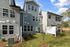 The back of a townhouse with a green lawn and a blue sky in the background at Abberly Alston Townhomes in Cary, NC