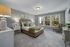 A comfortable bedroom featuring a cozy bed with plush bedding, a nightstand with a lamp, and a large window allowing natural light to fill the room at Abberly Alston Townhomes in Cary, NC