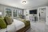 A comfortable bedroom featuring a cozy bed with plush bedding, a nightstand with a lamp, and a large window allowing natural light to fill the room at Abberly Alston Townhomes in Cary, NC