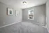 A bedroom with gray walls, carpet flooring, window for natural lighting and a cozy atmosphere at Abberly Alston Townhomes in Cary, NC