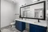 Elegant bathroom featuring blue cabinets and a large mirror at Abberly Foundry Apartments in Nashville, TN