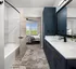 Chic bathroom featuring blue cabinets and a white bathtub at Abberly Foundry Apartments in Nashville, TN