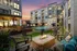 Outdoor lounge area featuring a fire pit and lounge chairs with a pool in the background at Abberly Foundry Apartments in Nashville, TN