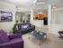Stylish living room with purple furniture and a kitchen in the background at Abberly Crest Apartments in Lexington Park, MD