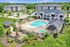 Aerial view of a luxurious resort pool with lounge chairs and umbrellas at Abberly Crest Apartments in Lexington Park, MD