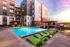 Swimming pool area featuring green lounge chairs in front of an apartment building at Abberly Foundry Apartments in Nashville, TN