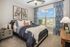 Bright and cozy bedroom with modern decor, featuring a plush bed, stylish wall art, large window with scenic view, and elegant furnishings.