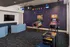 Chic entertainment room with arcade games, vibrant Pac-Man wall art, plush seating, and modern TV, perfect for leisure and fun.