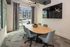 Modern meeting room with elegant design, featuring a sleek oval table, comfortable chairs, large wall-mounted TV, and abundant natural light.