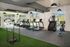 Modern fitness center featuring state-of-the-art treadmills, stair climber, exercise bikes, and a sled push station, all set in a bright, airy environment with large windows overlooking green spaces.