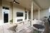 Modern outdoor patio with sleek furniture, cozy seating area, wall-mounted TV, and ceiling fans, ideal for relaxation and entertainment.