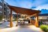 Inviting outdoor patio area with elegant wooden pergola, cozy seating, and twinkling string lights under a twilight sky, perfect for evening relaxation.
