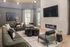 Elegant modern living room with stylish gray sectional sofa, sleek black coffee tables, and a cozy electric fireplace beneath a large flat-screen TV.