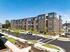 Modern four-story apartment complex with stylish brick facade, large windows, and lush landscaping. Ample parking and serene suburban surroundings enhance the appeal.