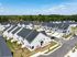 Modern suburban neighborhood with beautifully designed townhouses, surrounded by lush greenery and blue skies, offering a serene community living experience.