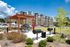 Modern apartment complex with outdoor BBQ area and pergola, surrounded by lush greenery and well-maintained landscaping, ideal for social gatherings.