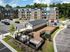 Modern apartment complex with contemporary design, spacious parking, and a fenced dog park under clear blue skies.