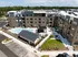 Modern apartment complex with a large outdoor pool, landscaped garden, and spacious patio area under clear blue sky.