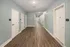 Modern hallway with elegant wood flooring and soft blue walls leading to secure apartment doors, illuminated by stylish ceiling lights.