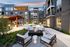 Modern apartment complex courtyard featuring elegant outdoor seating around a cozy fire pit, surrounded by lush greenery and softly lit walkways at dusk.