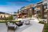 Luxurious apartment complex courtyard at dusk featuring cozy seating around a modern fire pit, a stylish pergola, and inviting pool area.