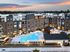 Elegant apartment complex with modern architecture, featuring a stunning illuminated pool and inviting outdoor lounge area at sunset.