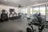 Modern fitness center with state-of-the-art exercise equipment, including treadmills, stair climber, and stationary bikes, all set in a bright, spacious room with large windows.