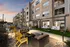 Modern apartment complex with a cozy outdoor seating area featuring a fire pit and vibrant yellow chairs under a stunning sunset.