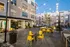 Chic apartment courtyard with inviting string lights, vibrant yellow seating, and modern grill area, perfect for social gatherings and relaxation.