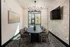 Modern conference room with elegant chandelier, large table, and artwork, overlooking a landscaped courtyard.