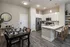 Modern open-concept kitchen and dining area featuring sleek white cabinetry, stainless steel appliances, and elegant wooden furniture.