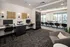 Modern communal workspace featuring sleek computer stations, artistic wall decor, and a bright conference area with large windows.