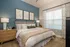 Elegant bedroom with cozy queen bed, modern abstract wall art, and soothing blue accent wall.