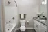 Elegant bathroom featuring a marble countertop, modern fixtures, and a chic white bathtub with chrome fittings.