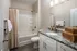 Elegant bathroom featuring a luxurious granite countertop, modern white cabinetry, and a pristine bathtub with chic beige shower curtain.
