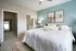 Bright and elegant bedroom with stylish decor, featuring a comfortable bed, modern artwork, and an en-suite bathroom with walk-in closet.