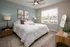 Tranquil bedroom with a plush white bed, elegant decor, and large window offering ample natural light.