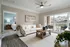 Bright and inviting living room with a cozy white sofa, elegant decor, and a view of a garden from the balcony.