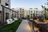 Charming apartment courtyard with cozy seating and swinging benches, surrounded by modern architecture and lush greenery.
