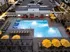 Elegant aerial view of a modern apartment complex featuring a well-lit swimming pool surrounded by vibrant yellow umbrellas and stylish lounge chairs, perfect for relaxation and leisure.
