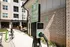 Contemporary apartment complex with electric vehicle charging station prominently featured in the foreground, highlighting eco-friendly amenities.