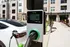 Modern apartment complex with electric vehicle charging station in front, highlighting eco-friendly amenities and contemporary living.