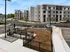 Modern apartment complex with spacious parking and landscaped surroundings, featuring contemporary architecture and urban living amenities.