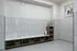 Modern and sleek mudroom with tiled walls and flooring, featuring built-in storage with baskets and potted plants, and a playful framed bulldog artwork.