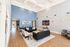 Spacious contemporary lounge with elegant high ceilings, cozy seating area, chic decor, and a large wall-mounted TV.