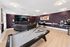 Luxurious entertainment room featuring a sleek pool table, cozy seating area with a large flat-screen TV, and a modern coffee and tea bar.