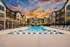Luxurious apartment complex with a stunning outdoor pool area, surrounded by elegant architecture and vibrant sunset skies.