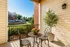 Charming balcony with elegant wrought iron furniture, vibrant potted flowers, and scenic view of a modern apartment complex.