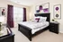 Elegant bedroom with stylish black furniture, vibrant purple accents, and modern decor for a luxurious living ambiance.