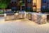 Elegant outdoor barbecue area with stainless steel grills, stone countertops, and ambient lighting, perfect for entertaining in a stylish apartment community.